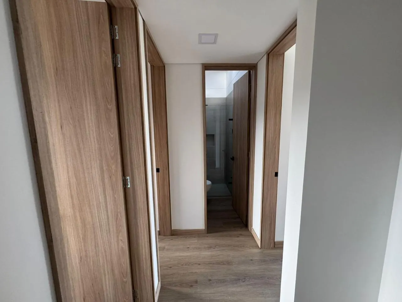 Hall del segundo nivel con puertas en madera hacia las alcobas y el baño.