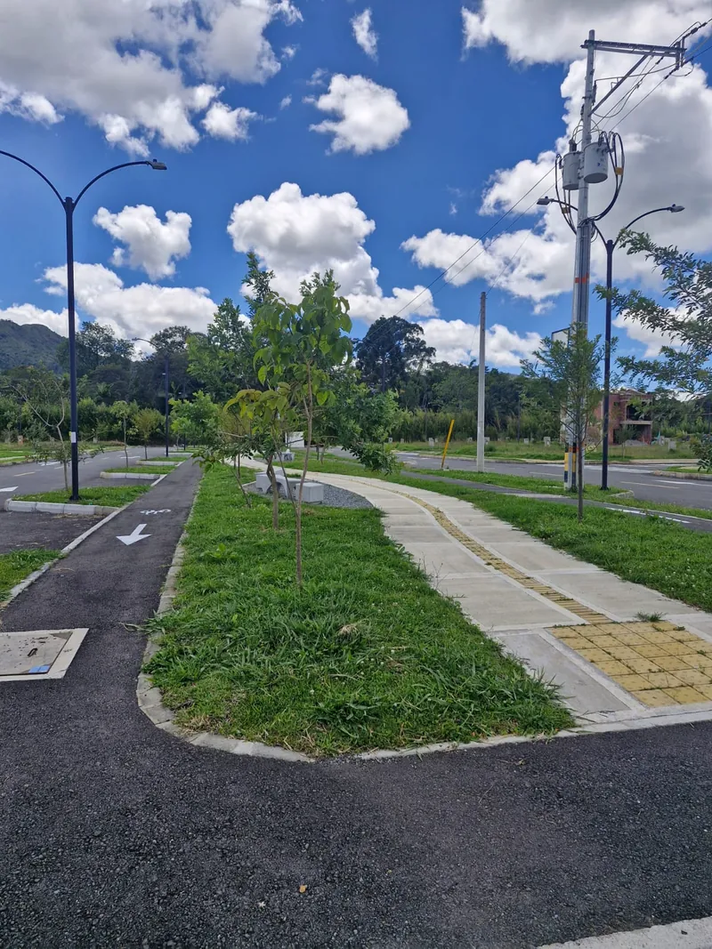 Sendero peatonal y ciclorruta entre zonas verdes arborizadas con alumbrado público, dentro del urbanismo terminado en La Ceja, Antioquia