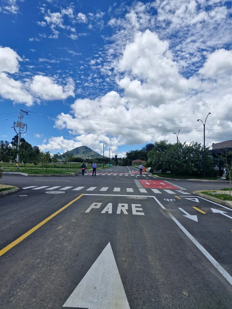 Vías pavimentadas con señalización, cruce peatonal y demarcación de ciclorruta, con el cerro al fondo, en La Ceja, Antioquia
